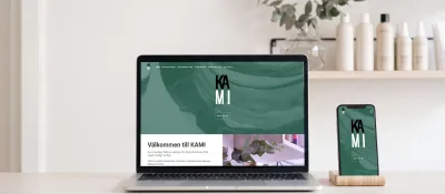 KAMI:s webbsida på en laptop och en mobil i en ljus frisersalong